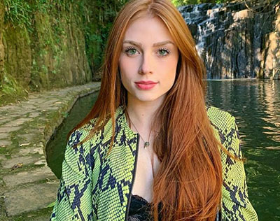 Foto ilustrativa de uma mulher ruiva ao ar livre, representando uma Sugar Baby.